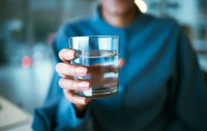Sinises särgis naine ulatab klaasi vett „Culligan“ veeautomaadist.